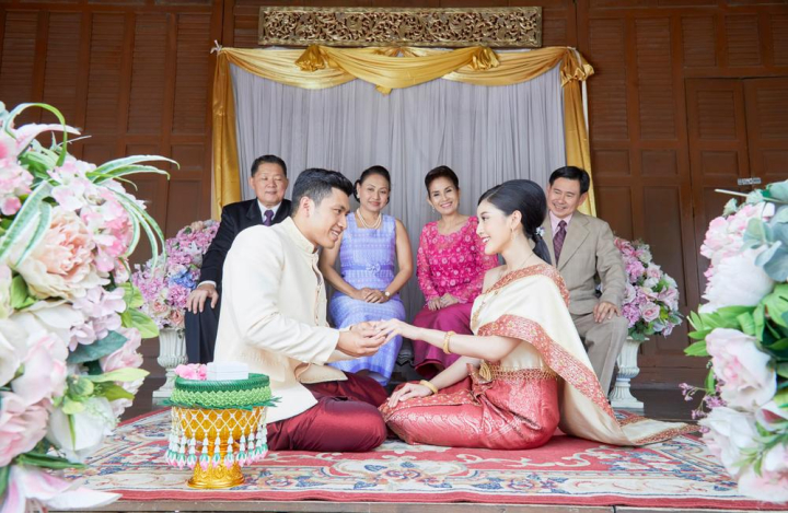 bride,groom,wearing,ring,finger,sitting,smiling,male,female,man,woman,couple,people,husband,culture,buddhist,buddhism,traditional,vintage,wife,bridal,wedding,marriage,married,thai,thailand,thai style,asia,asian,celebration,wedding dress,gratitude,ceremony,religion,religious,elegance,hand,family,parrents,aunt,elegant,decoration,flower,engagement,bloom,floral,relatives,six,group,parents,blessing,congratulation,khan maak,betel bowl,xframe